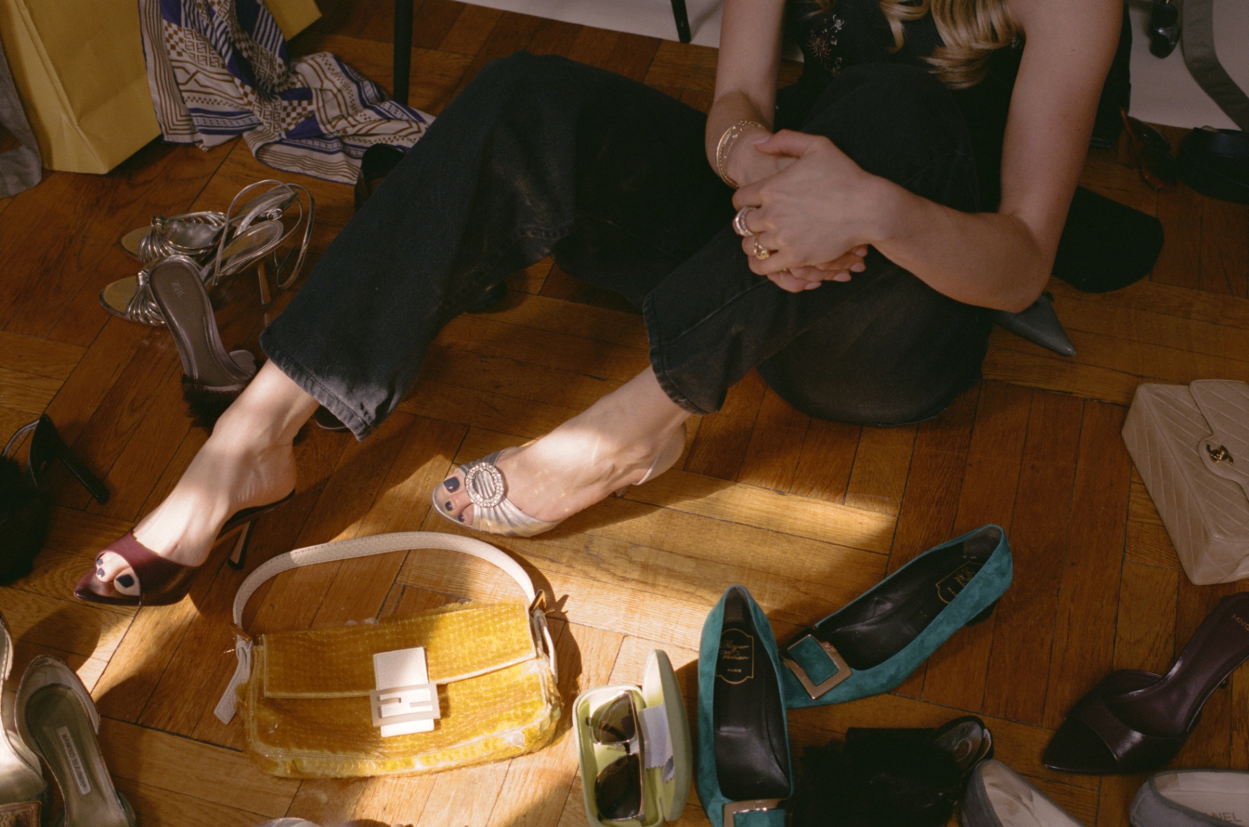 Curated heels, bags, and accessories arranged on a warm wooden floor